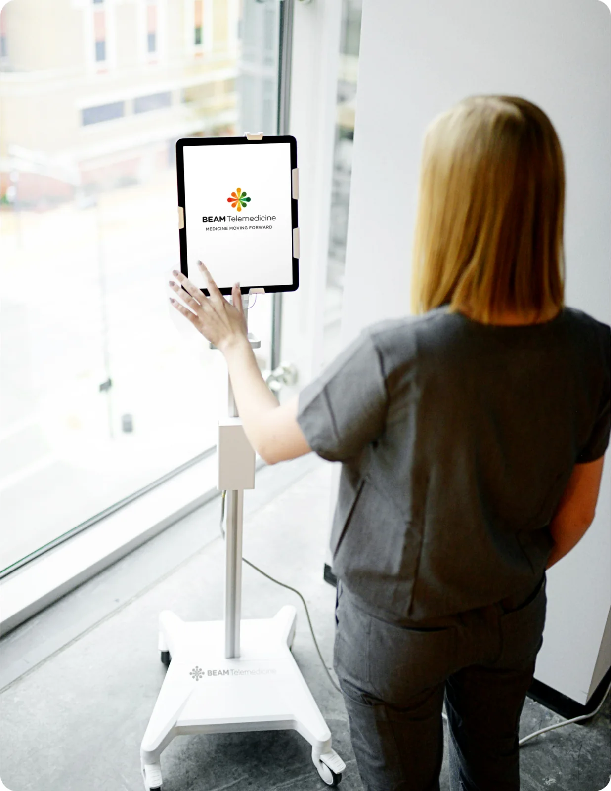 A Beam clinician using a telemedicine cart at a hospital window